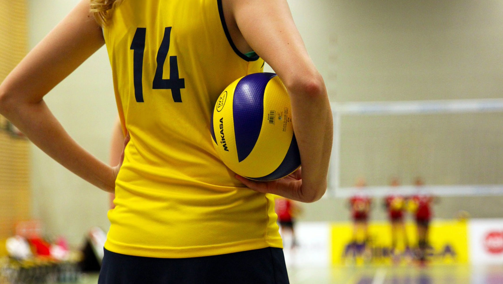 Volleybollspelare med en boll under armen.