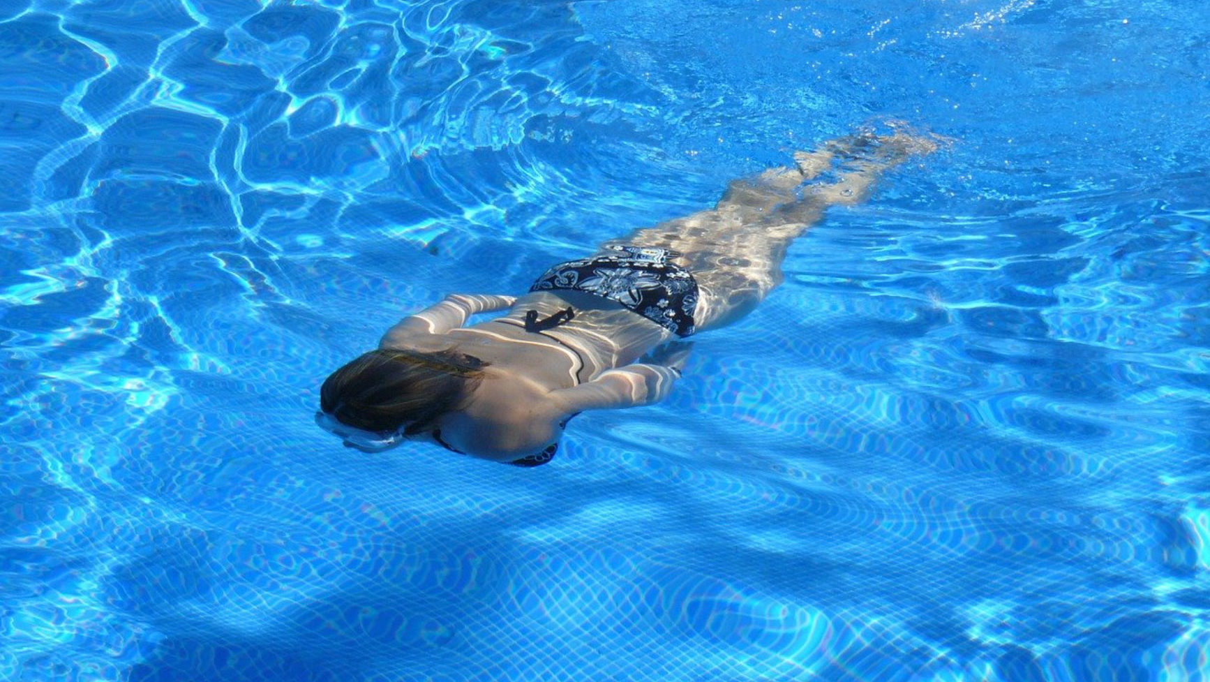 En kvinna dyker i simbassängen.