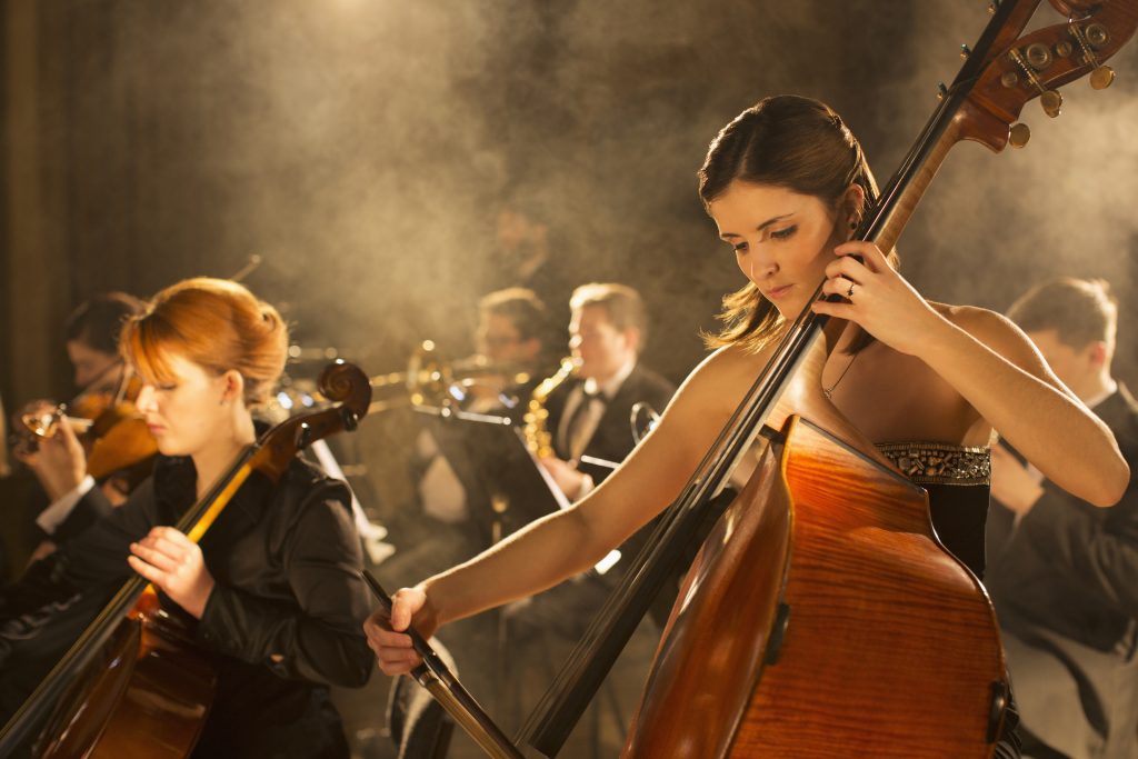 Image of an orchestra with a woman in the foreground playing a double bass.